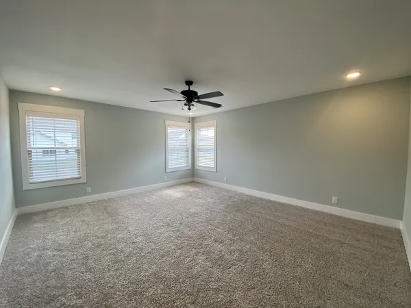 an empty room with a ceiling fan and window