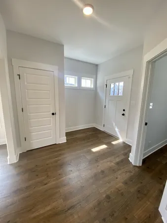 an empty room with wooden floor & windows and bathroom