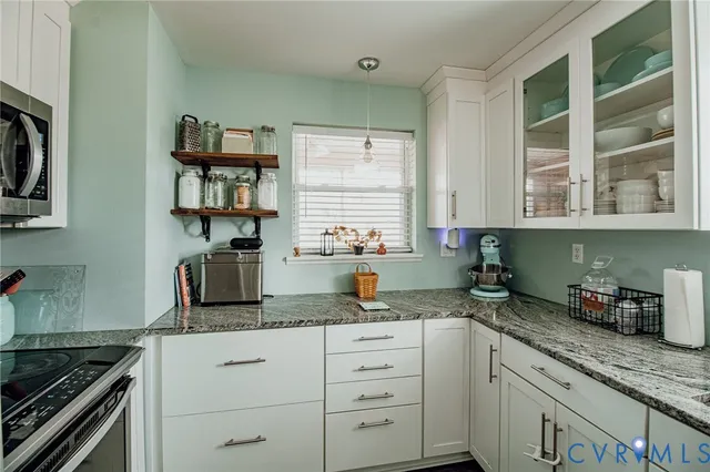 a kitchen with granite countertop white cabinets and window