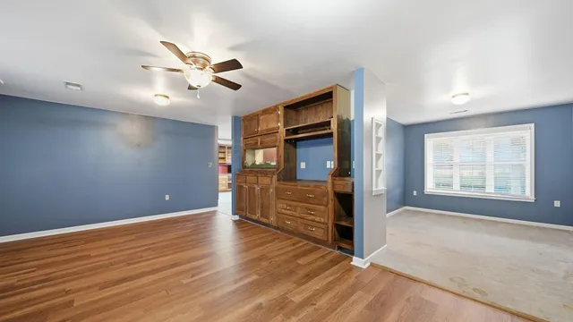a view of an empty room with window and wooden floor