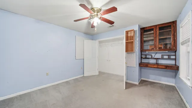 an empty room with bookshelf and chandelier fan