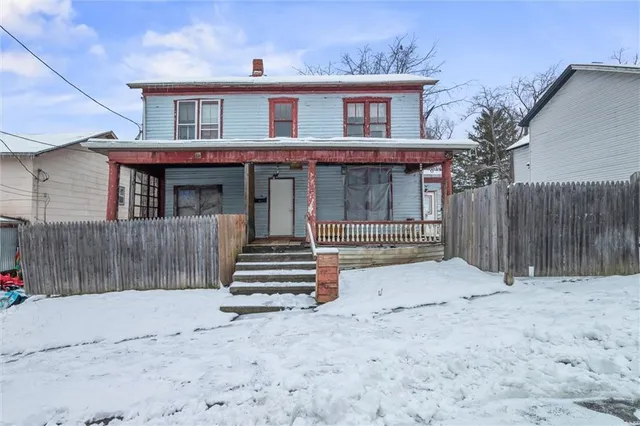 a view of a house with wooden fence and large trees