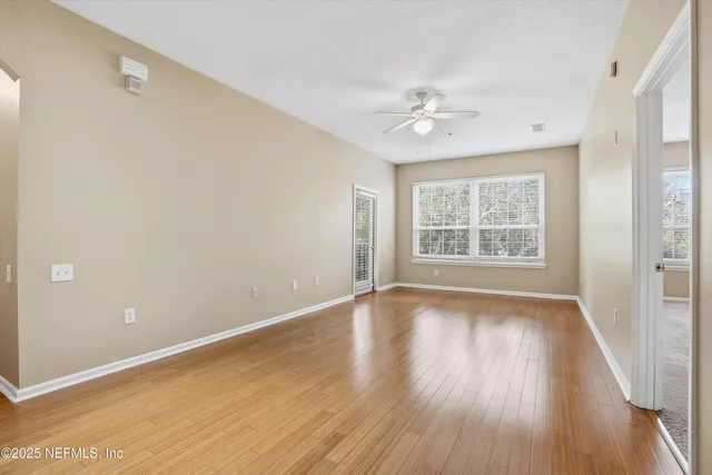 an empty room with windows and fan