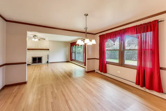 a view of a room with wooden floor fireplace and windows