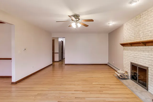 a view of an empty room with wooden floor and a fireplace