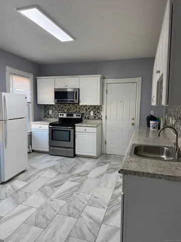 a kitchen with granite countertop a sink stove and refrigerator
