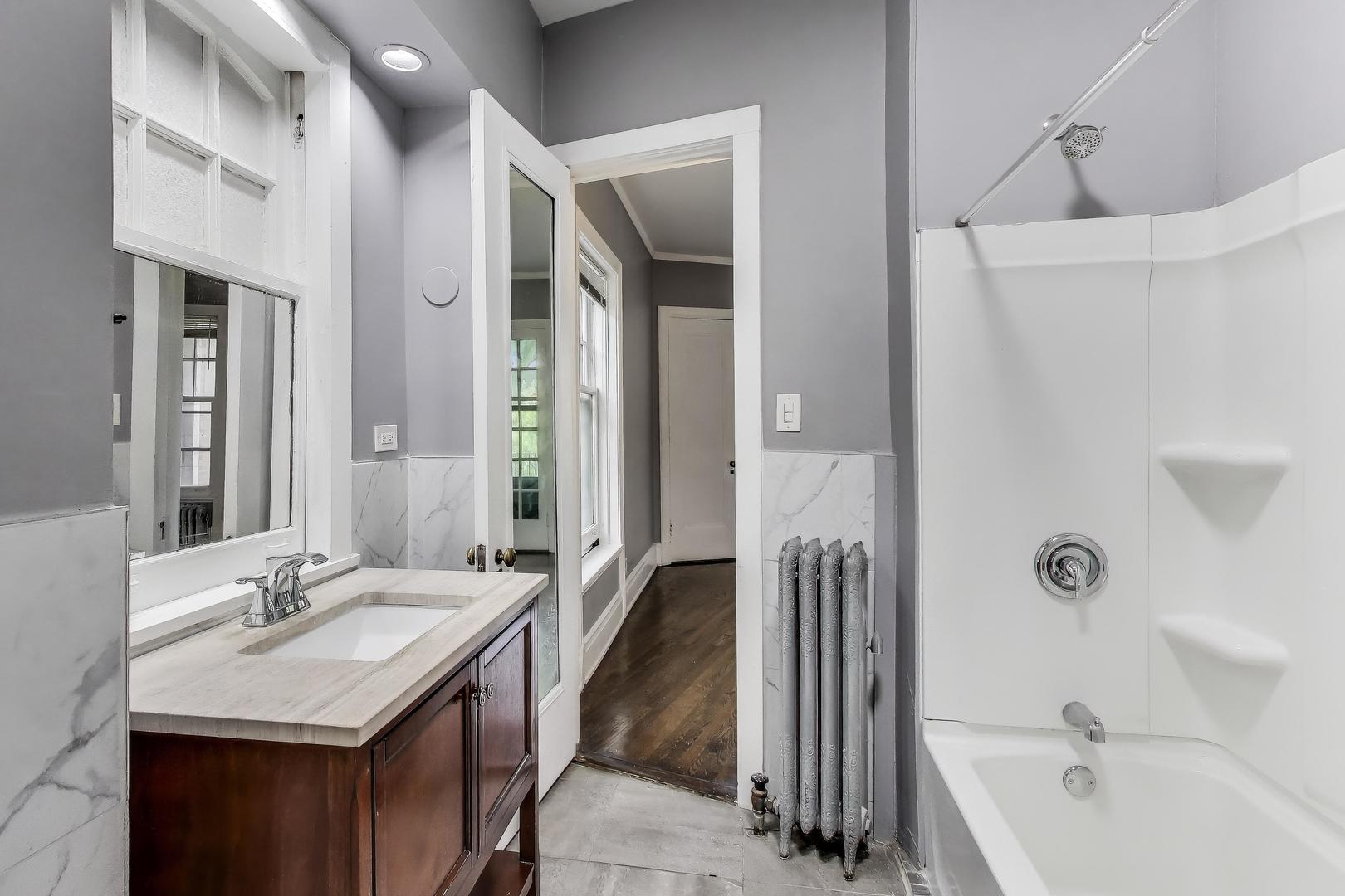 1615 East Hyde Park Boulevard, Unit 2 Chicago, IL 60615 - Photo 10 of 19 a bathroom with a tub sink and mirror