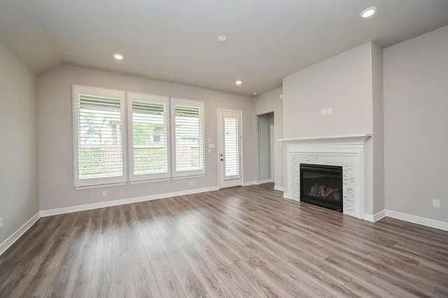 an empty room with wooden floor fireplace and windows