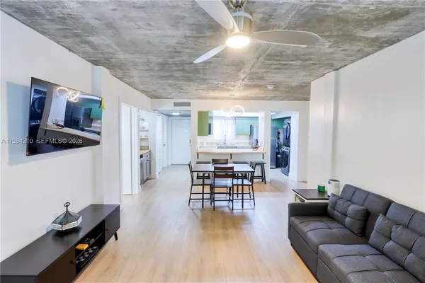 a kitchen with stainless steel appliances kitchen island granite countertop a table chairs and a refrigerator