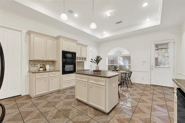 a kitchen with stainless steel appliances kitchen island granite countertop a stove a sink a refrigerator a dining table and chairs with wooden floor