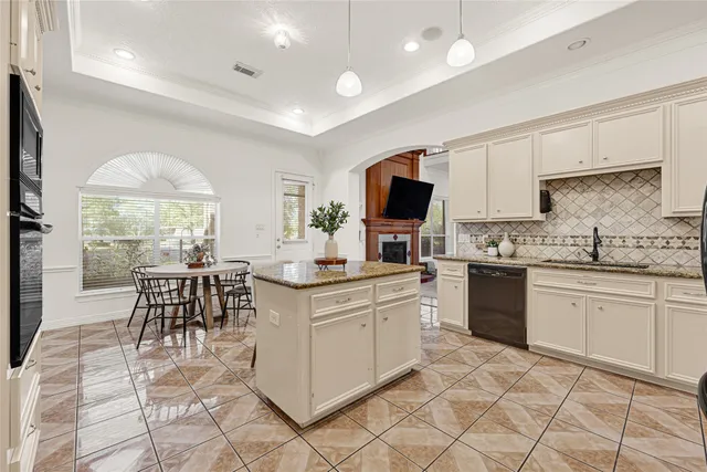 a kitchen with stainless steel appliances granite countertop a stove top oven a sink dishwasher a dining table and chairs with wooden floor