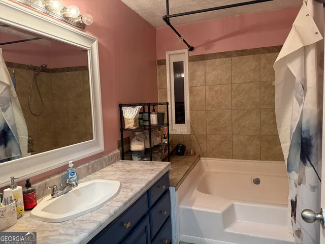 a bathroom with a granite countertop sink a mirror a bathtub and shower