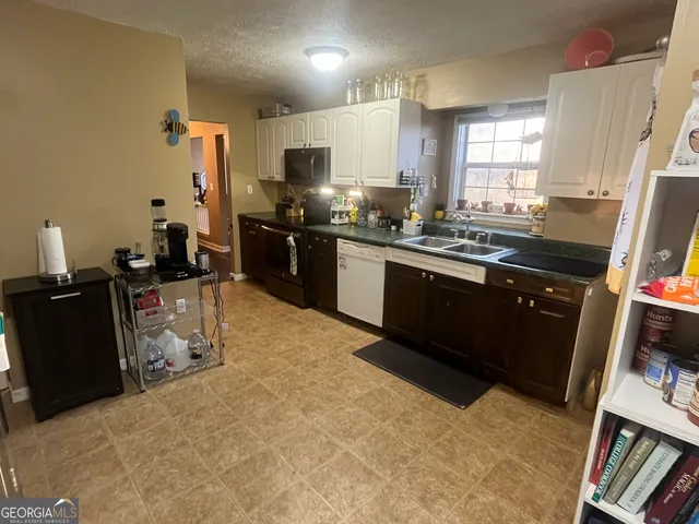 a kitchen with granite countertop a refrigerator stove and sink