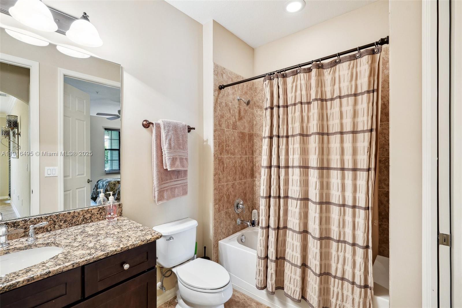 9064 Capistrano Street North, Unit 5004 Naples, FL 34113 - Photo 17 of 27 a bathroom with a granite countertop sink a toilet a mirror a vanity and shower