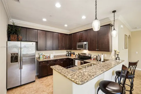 a kitchen with stainless steel appliances granite countertop a sink refrigerator and cabinets