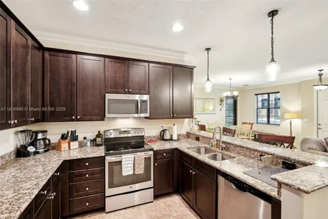 a kitchen with granite countertop a sink a counter space appliances and cabinets