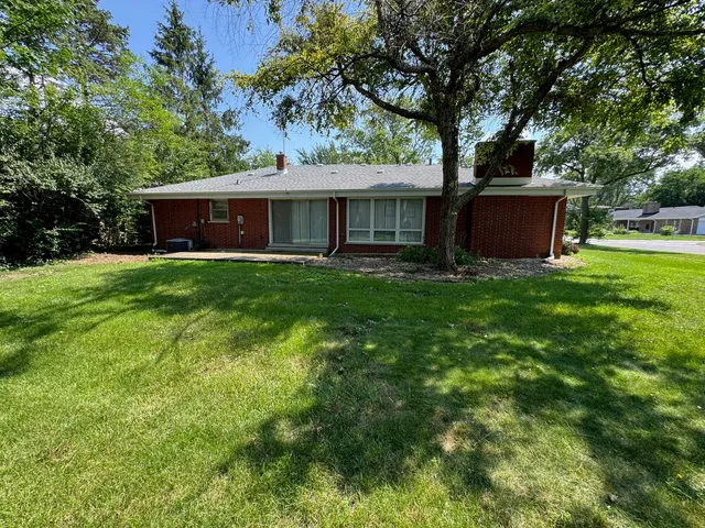 a front view of a house with yard and tree