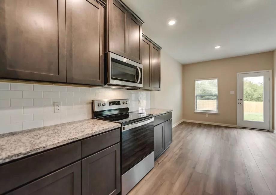 296 Wandering Stream Way Princeton, TX 75407 - Photo 3 of 7 a kitchen with granite countertop wooden cabinets a sink and dishwasher