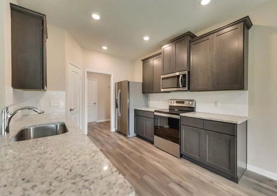 296 Wandering Stream Way Princeton, TX 75407 - Photo 4 of 7 a kitchen with stainless steel appliances granite countertop a sink and a stove top oven