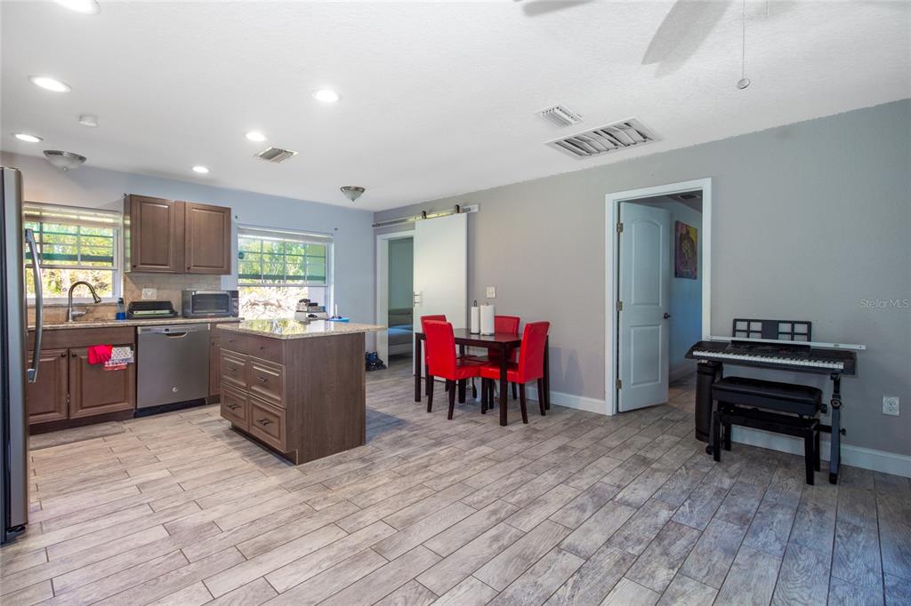 6447 Brandy Drive Spring Hill, FL 34607 - Photo 11 of 25 a kitchen with stainless steel appliances kitchen island granite countertop a dining table chairs and a refrigerator