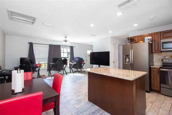 a kitchen with stainless steel appliances granite countertop a table chairs refrigerator and a sink