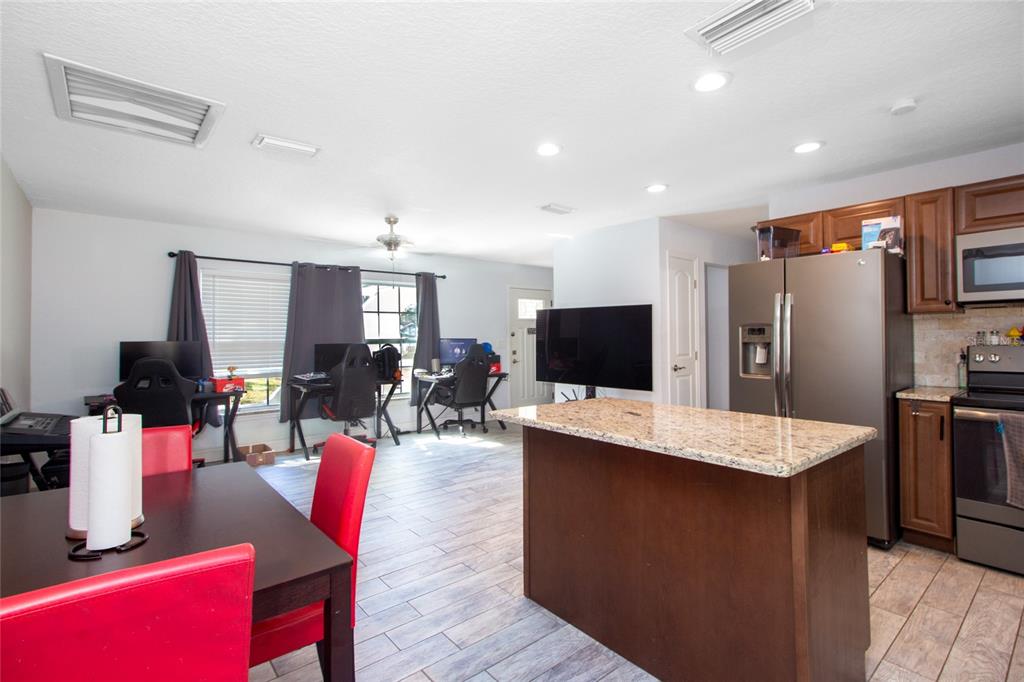 6447 Brandy Drive Spring Hill, FL 34607 - Photo 8 of 25 a large living room with stainless steel appliances kitchen island granite countertop a couch chairs and a flat screen tv