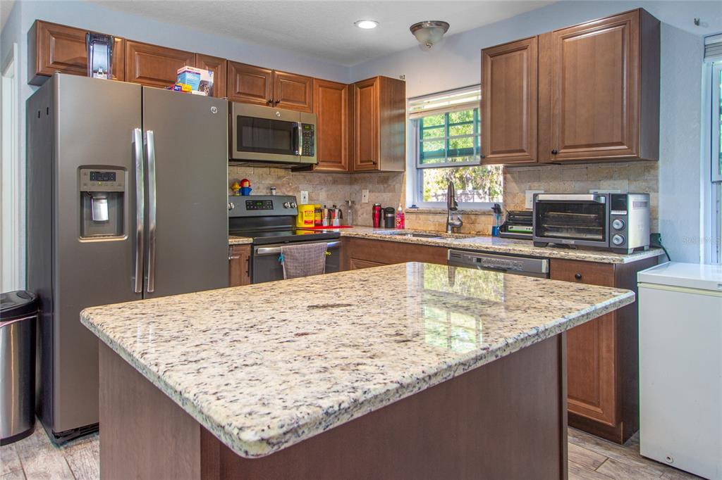 6447 Brandy Drive Spring Hill, FL 34607 - Photo 9 of 25 a kitchen with stainless steel appliances granite countertop a table chairs refrigerator and a sink