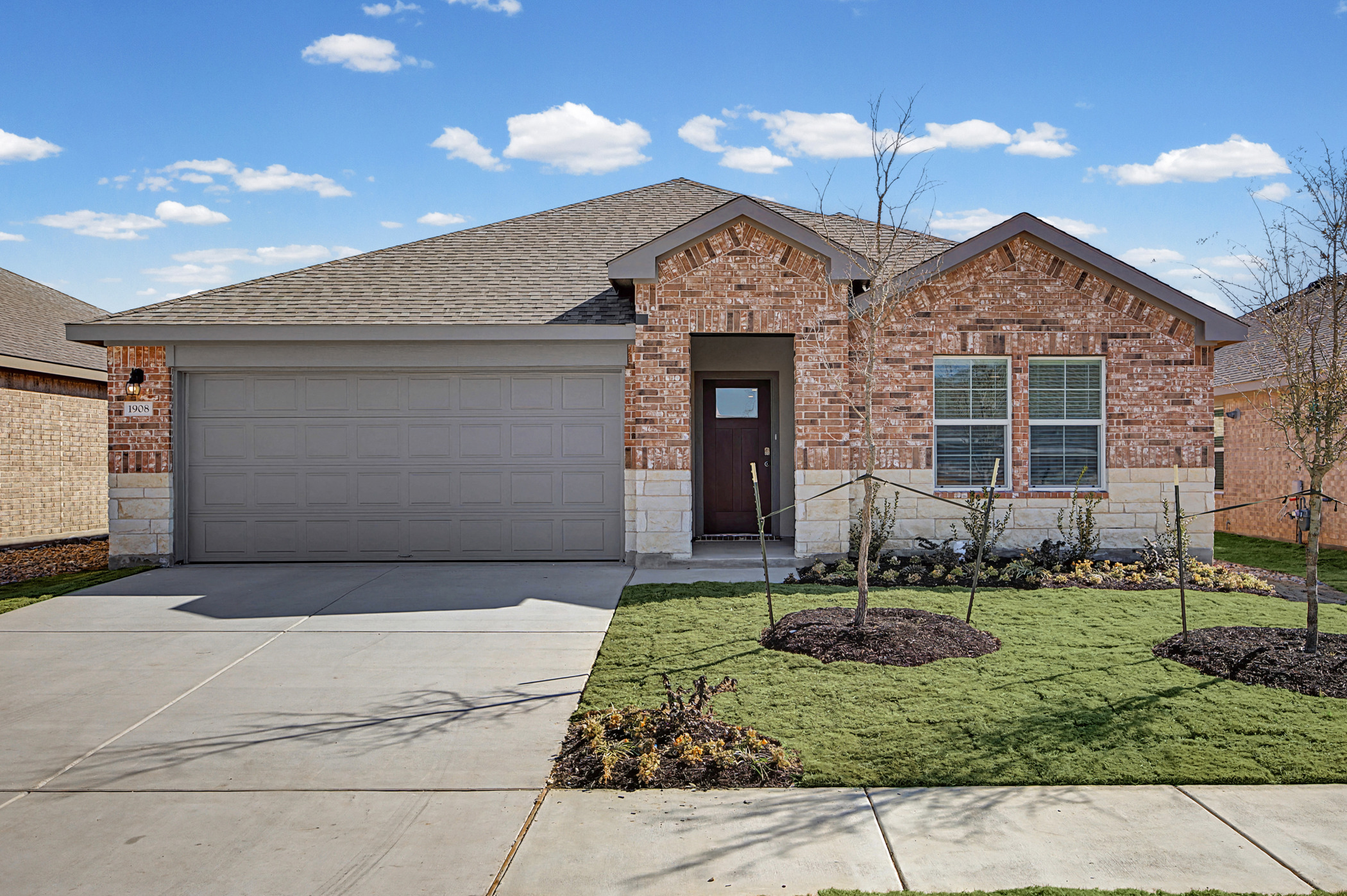 Ranch-style home with brick siding, a front yard, driveway, an attached garage, and a shingled roof