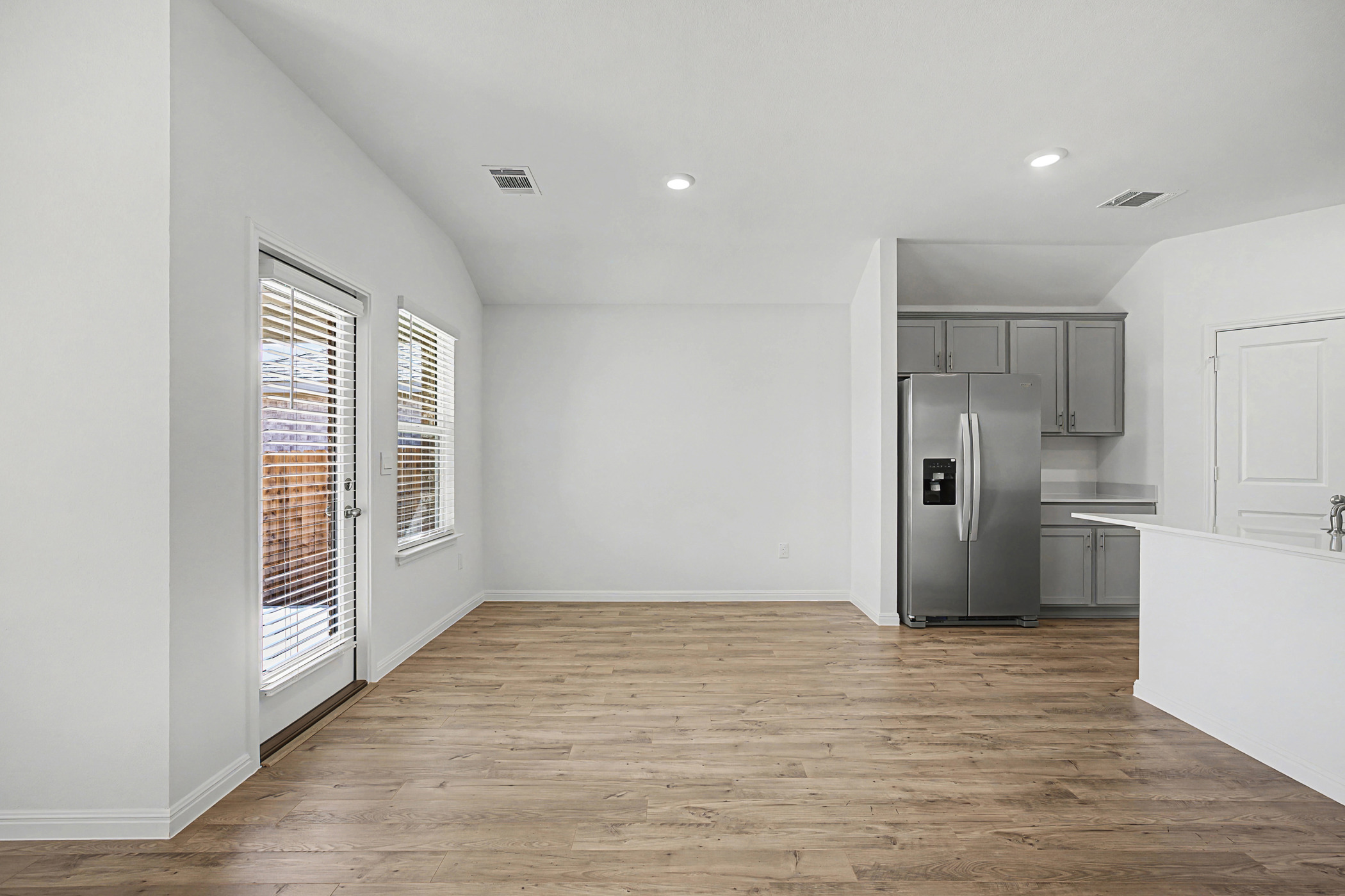 1908 Pogonip Place Leander, TX 78641 - Photo 6 of 21 Kitchen with gray cabinets, stainless steel fridge with ice dispenser, light wood-type flooring, light countertops, and recessed lighting
