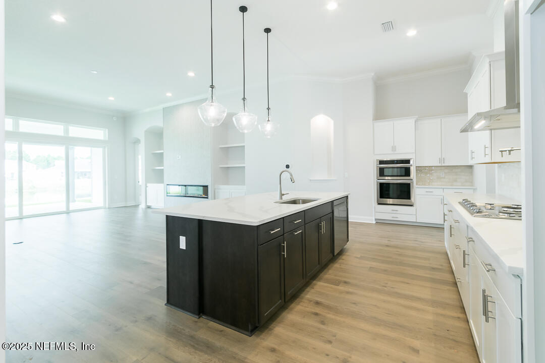 303 Eagle Moon Lake Drive St. Augustine, FL 32092 - Photo 18 of 35 a large kitchen with kitchen island a sink a center island a stove and a wooden floor