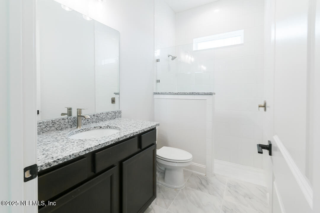 303 Eagle Moon Lake Drive St. Augustine, FL 32092 - Photo 28 of 35 a bathroom with a granite countertop sink a toilet and a mirror