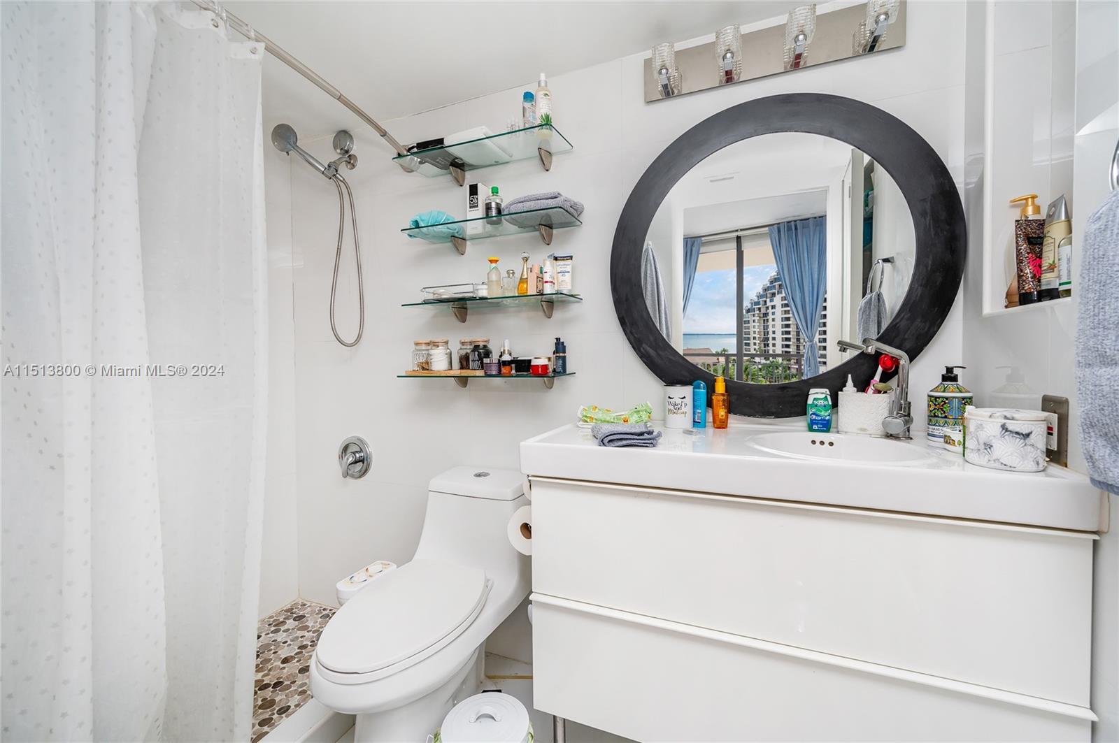 540 Brickell Key Drive, Unit 905 Miami, FL 33131 - Photo 17 of 43 a bathroom with a toilet mirror vanity and clock on the wall