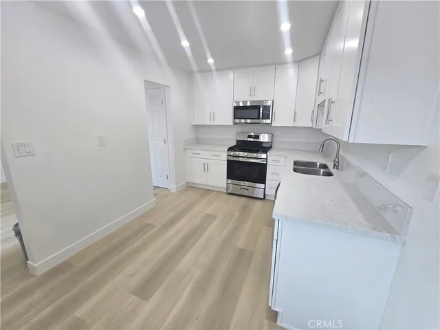 a kitchen with granite countertop a sink stove and refrigerator