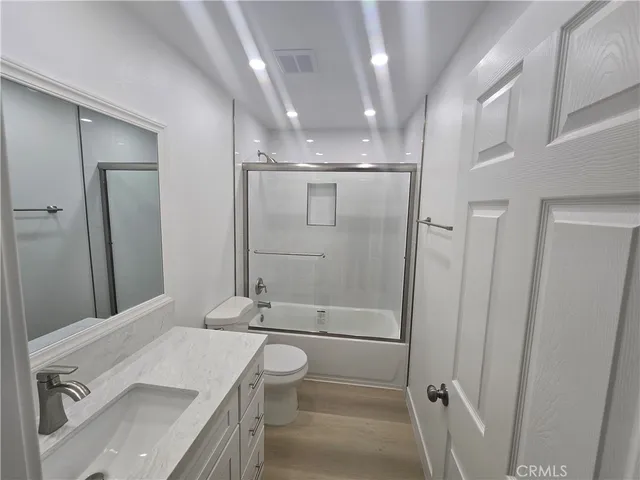 a bathroom with a granite countertop sink a toilet and shower