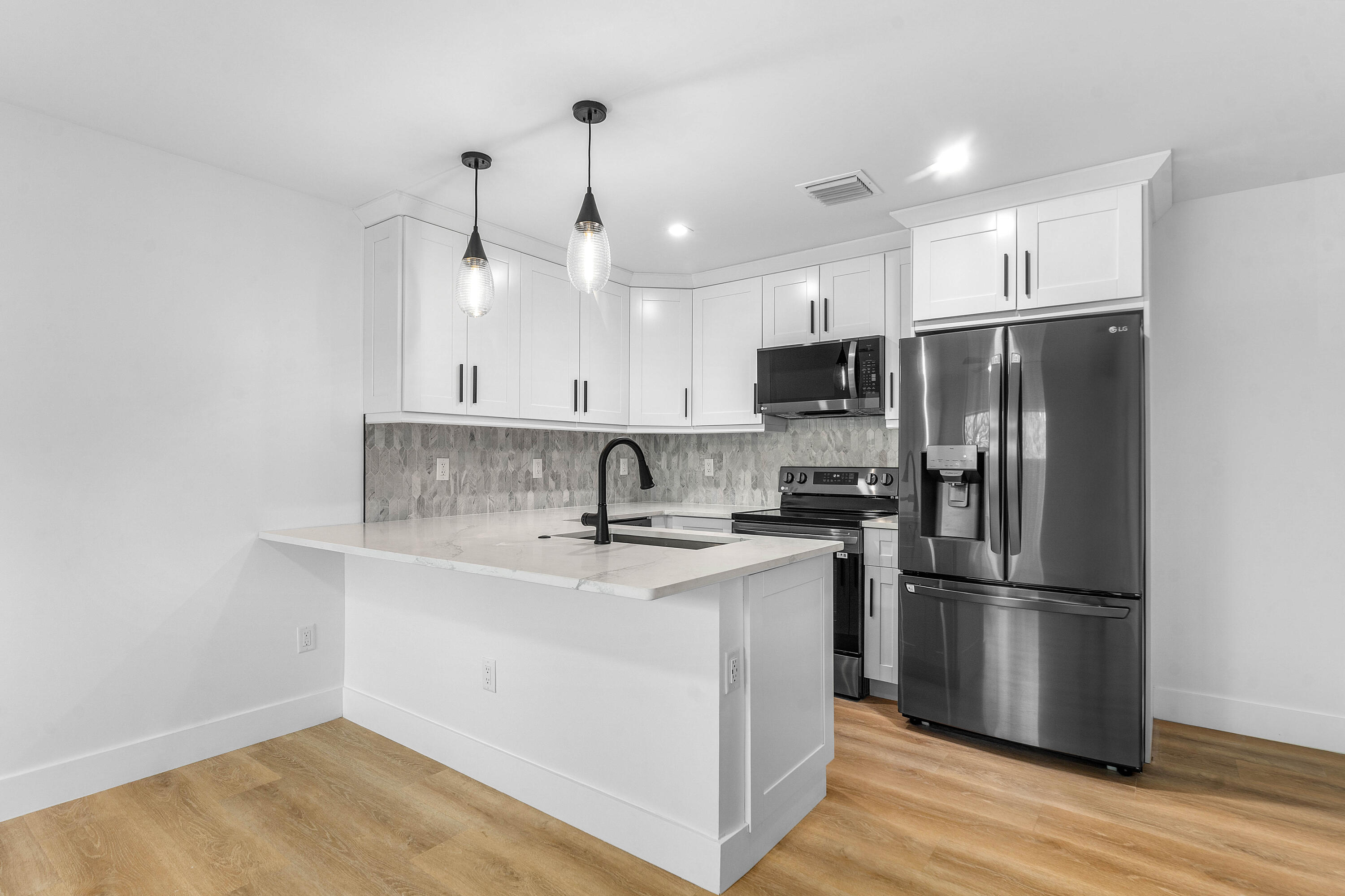 5701 Old Orange Road Jupiter, FL 33458 - Photo 36 of 46 a kitchen with stainless steel appliances granite countertop a refrigerator a sink a stove and white cabinets