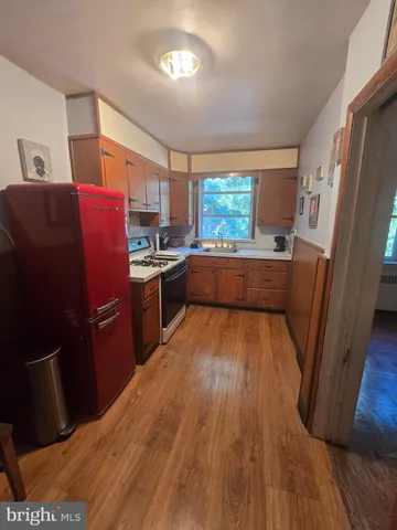 a kitchen with stainless steel appliances a refrigerator a sink dishwasher a stove and white countertops with wooden floor