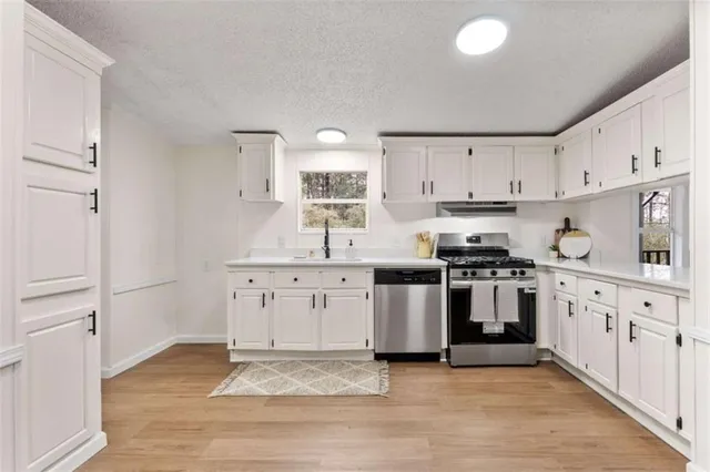 a kitchen with granite countertop a sink stove and cabinets