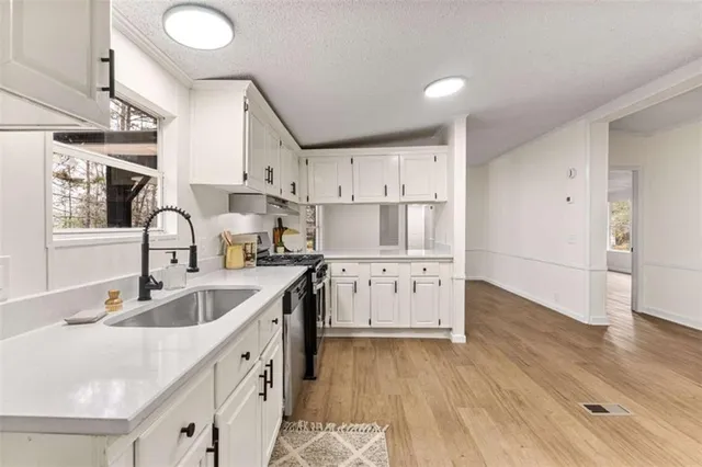 a kitchen with granite countertop a sink stove and cabinets