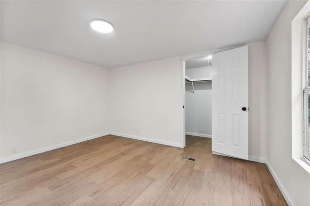 a view of an empty room with wooden floor and closet