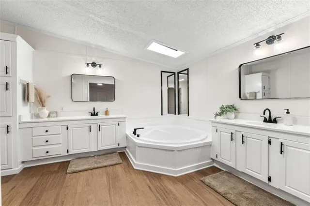 a spacious bathroom with double vanity a mirror a bathtub and sink