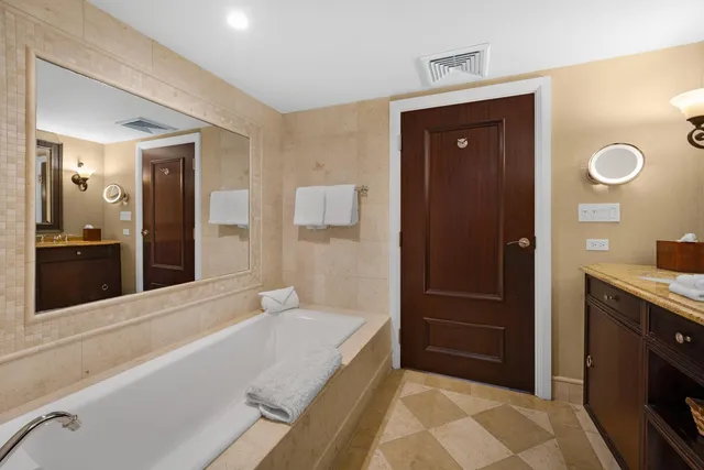 a spacious bathroom with a tub sink and mirror