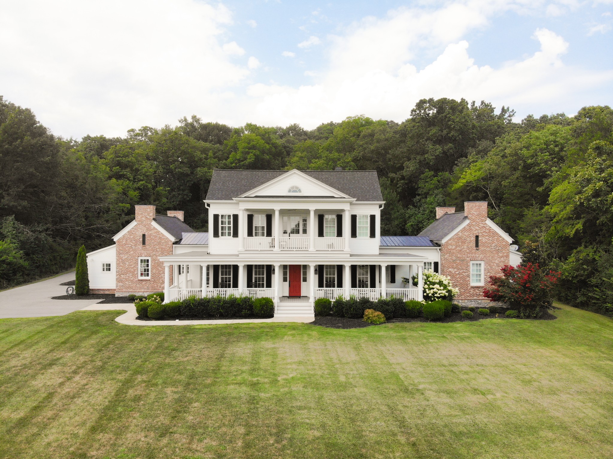 a front view of a house with a garden and trees