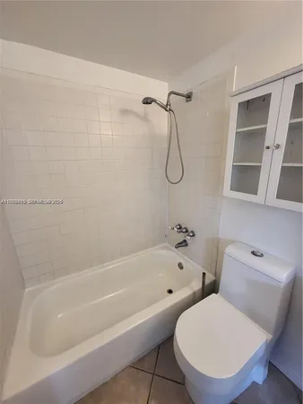 a white bath tub sitting next to a white toilet and a shower