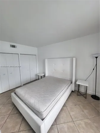 a room with a bed and white cabinets