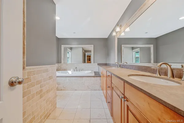 a bathroom with a granite countertop sink a mirror and a bathtub