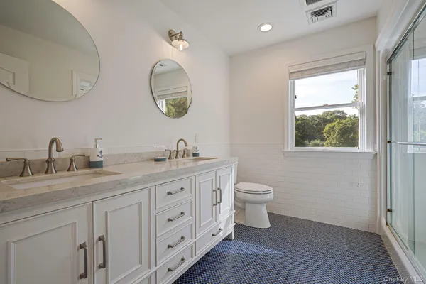 a spacious bathroom with a double vanity sink a toilet and a mirror