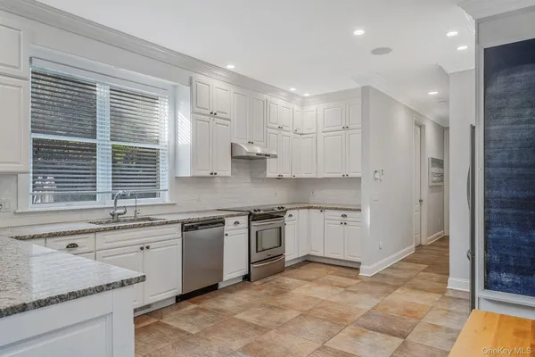 a large kitchen with stainless steel appliances kitchen island granite countertop a table and chairs in it