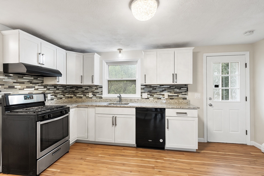 21 Crescent Street, Unit D Lawrence, MA 01841 - Photo 23 of 25 a kitchen with stainless steel appliances granite countertop a stove top oven a sink dishwasher and a refrigerator with wooden floor