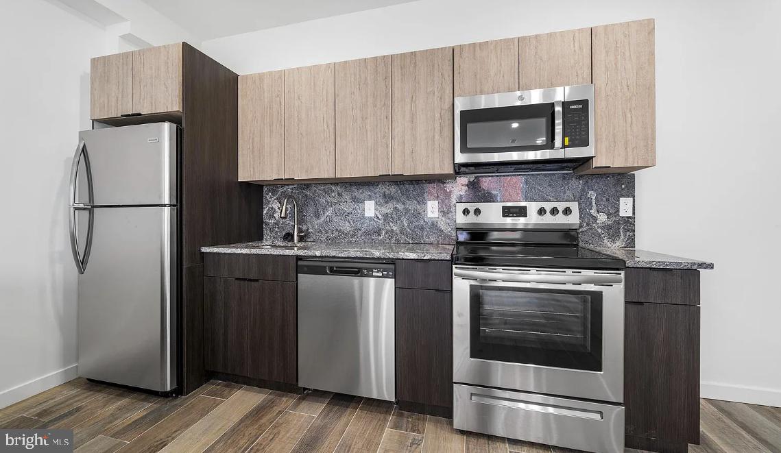 300 Budd Street, Unit B2 Philadelphia, PA 19104 - Photo 6 of 23 a kitchen with stainless steel appliances granite countertop a refrigerator stove and microwave