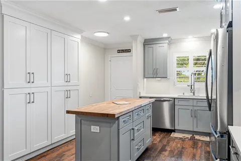 a kitchen with stainless steel appliances kitchen island granite countertop a refrigerator oven a stove top oven with a dining table and chairs with wooden floor